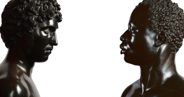 Photograph. From opposite ends of a long composition, two black stone busts face each other. To our left, Antico’s sculpture shows a person with full, curly hair, a straight nose, a moustache, and defined cheekbones. His chin is slightly tucked in. To our right, the face of Harwood’s sculpture seems to look levelly back. It depicts a Black man with short, curly hair, a softly curved nose, and full lips which are closed. Both are shown to the tops of their shoulders.