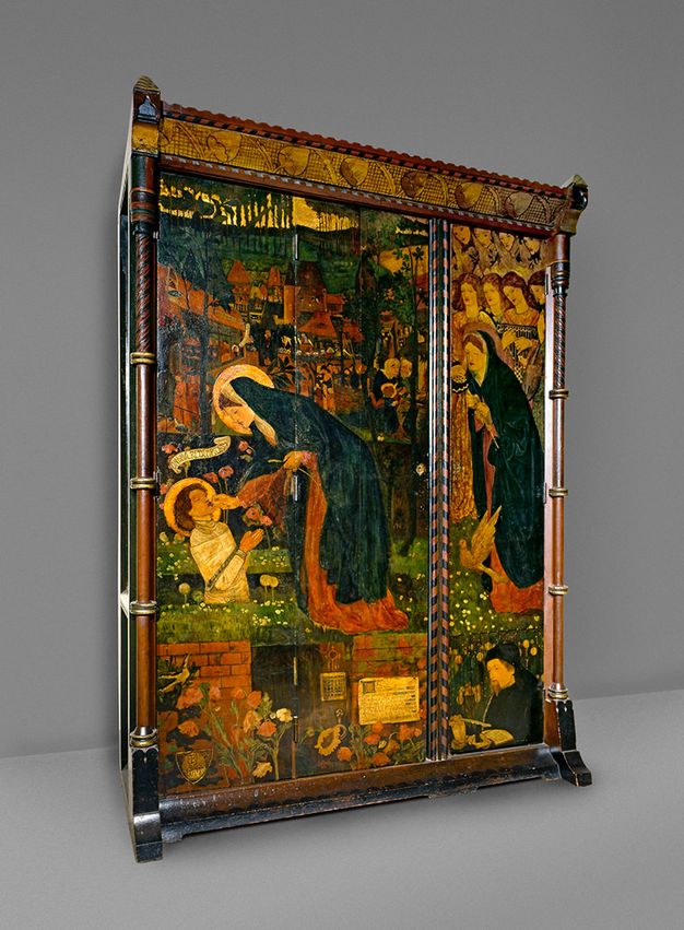 Furniture. This wardrobe is painted with a scene of a woman, the Virgin Mary, reaching towards the mouth of a boy who kneels in prayer. Both have halos, and they are set in front of a detailed landscape with further figures to our right.